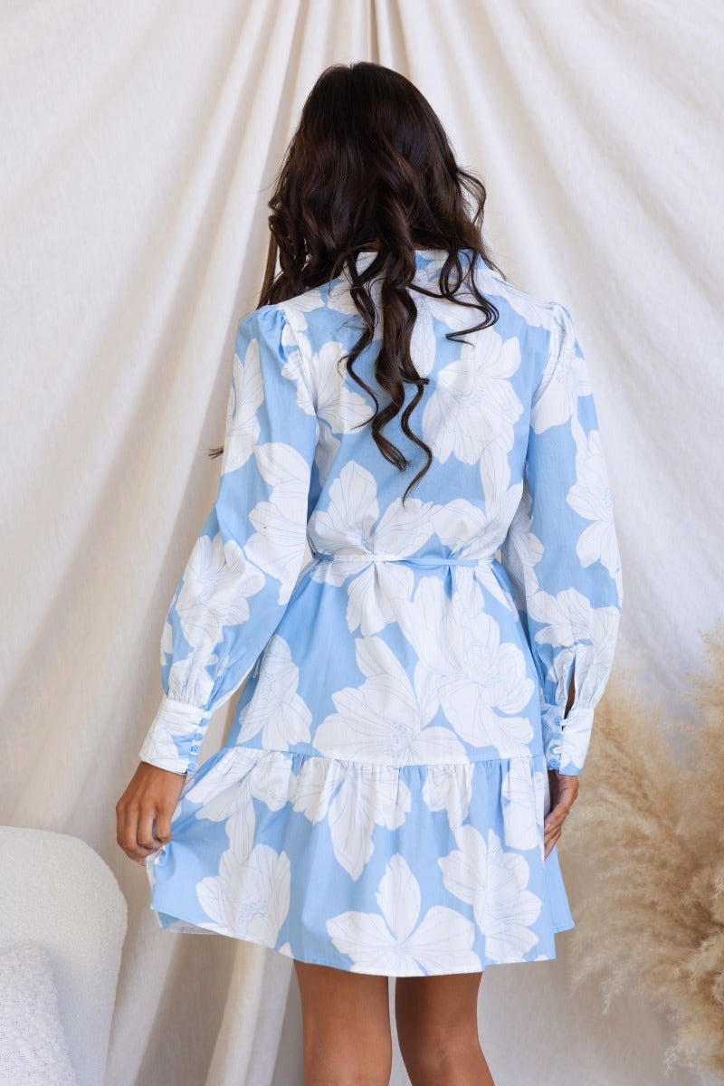 Back view of Mellow Dress featuring a blue floral print, button-up front, and removable tie detail.