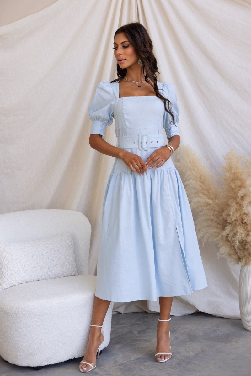 Innis Midi Dress in light blue, featuring square neckline, puff sleeves, and removable belt, styled elegantly in a soft setting.