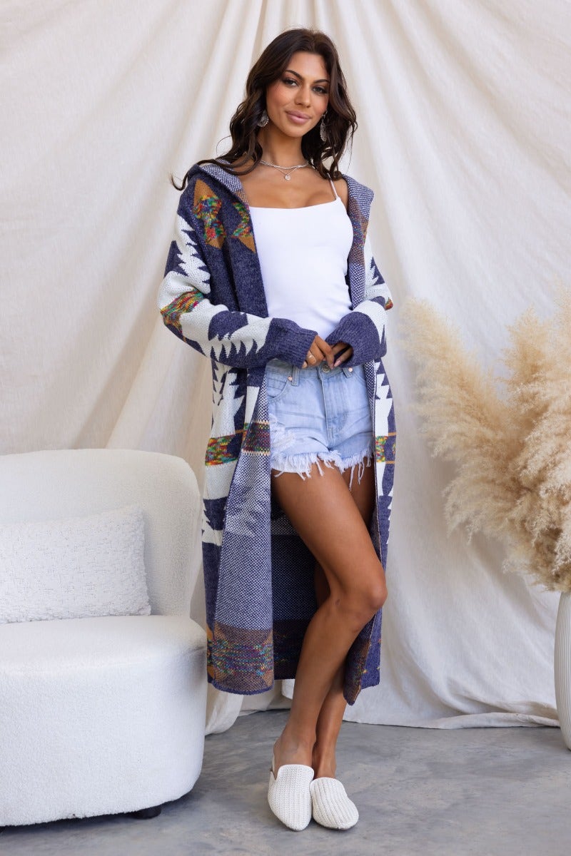 Navy longline cardigan with hood, pockets, and tribal print, styled over a white tank and denim shorts.