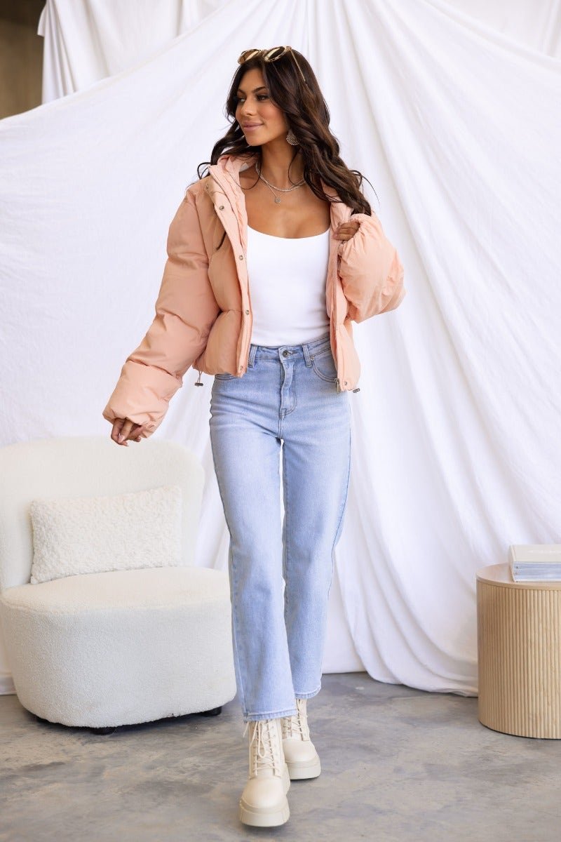 Model wearing a stylish Vinna Puffer Jacket paired with light jeans, posing against a soft white backdrop.