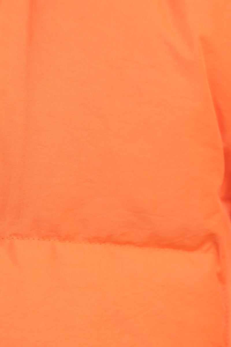 Close-up of vibrant orange fabric of the Avril Puffer Jacket, showcasing its smooth texture and puffer detail.