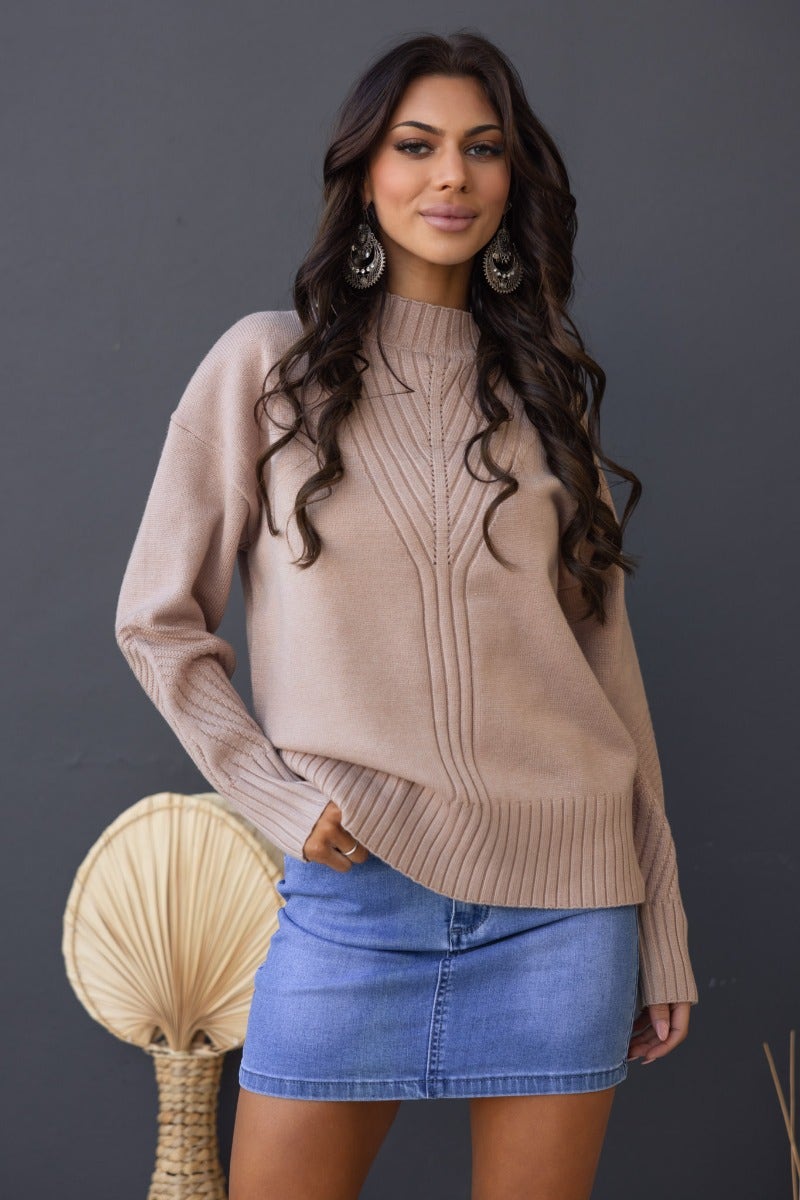 Model wearing a beige ribbed knit Cuba Jumper with mock neckline, styled with a denim skirt.