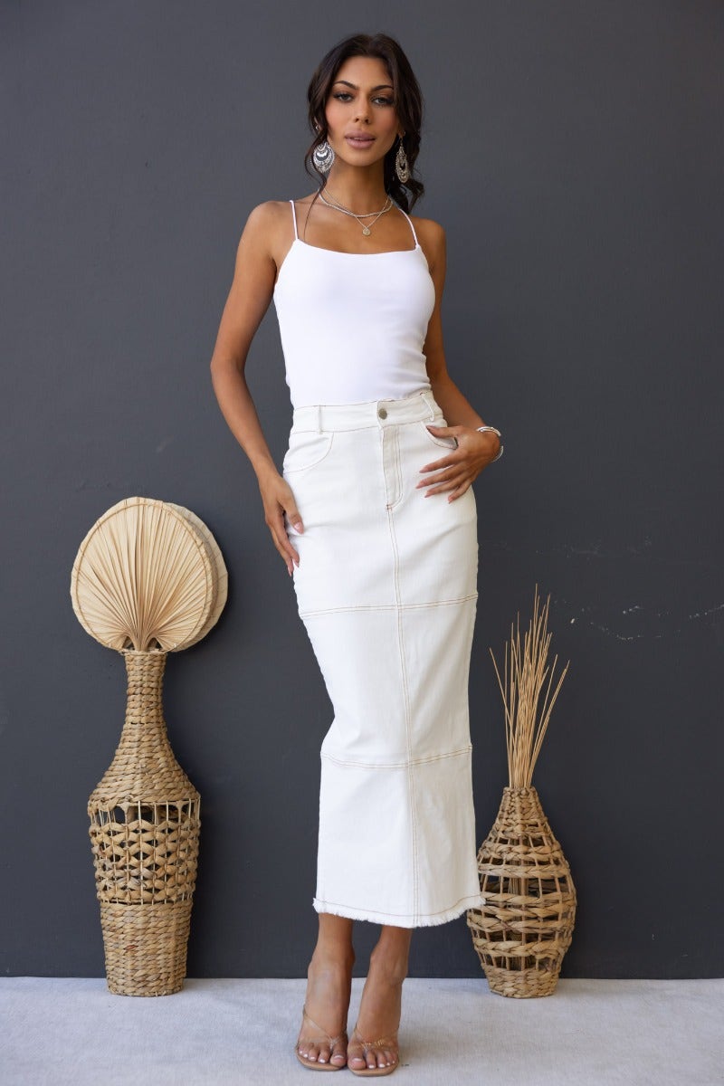 Model wearing a Caria Denim Midi Skirt in white, showcasing the mid-high waist and frayed hemline.