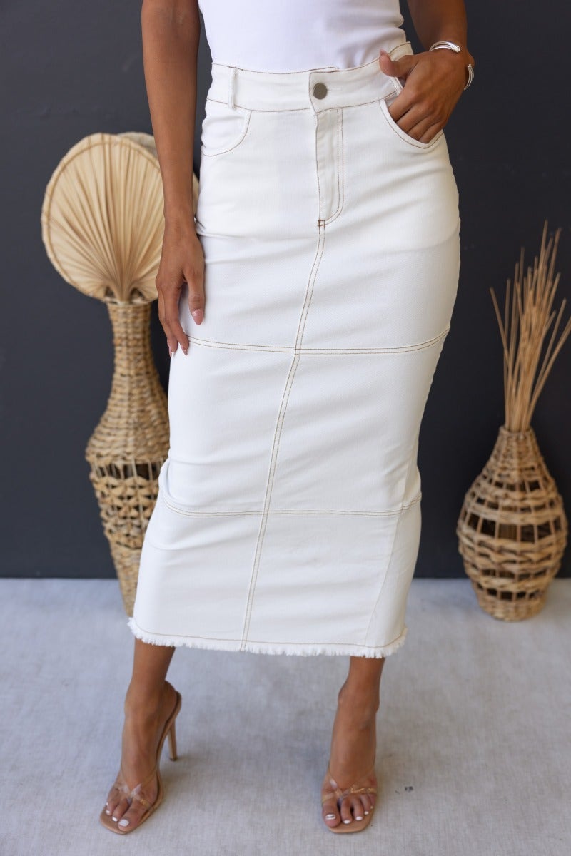 Caria Denim Midi Skirt featuring a mid-high waist fit, front and back pockets, frayed hemline, and stretchy material.