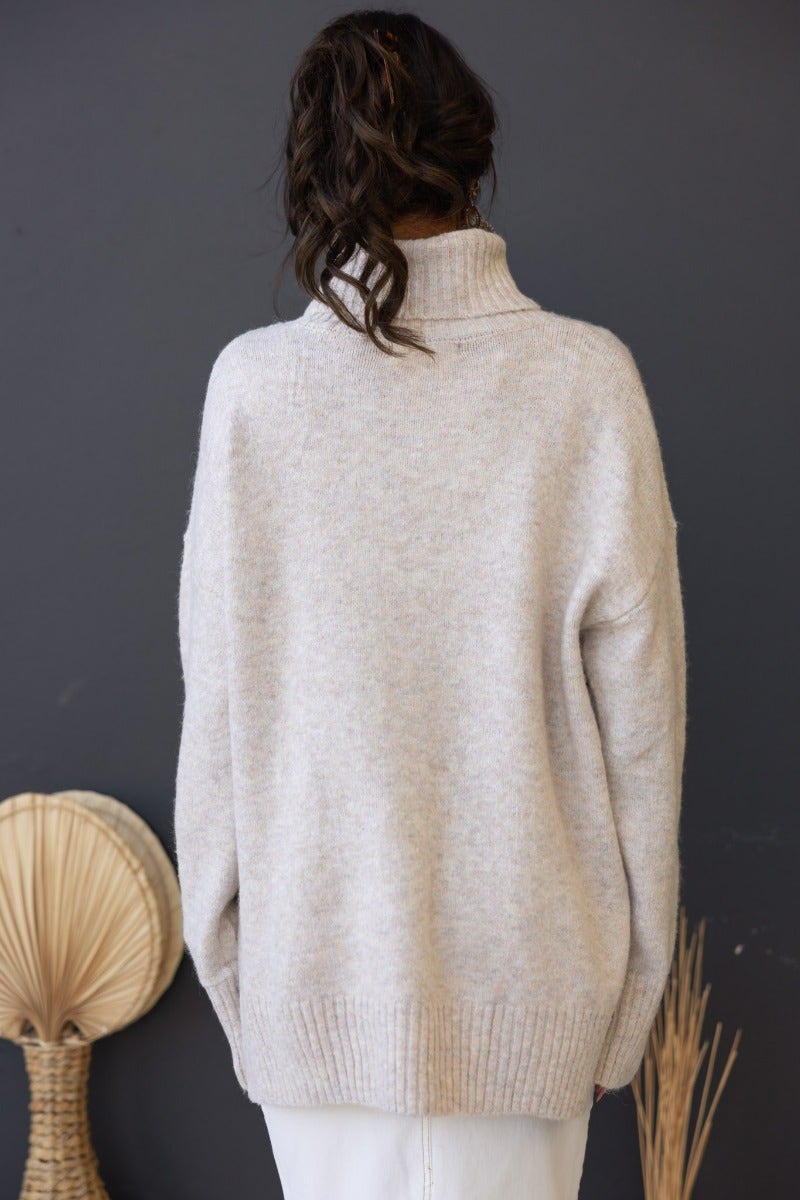Back view of a relaxed fit ribbed knit Orion Jumper with turtle neckline, showcasing its soft beige material.