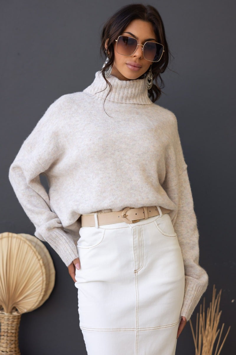 Model wearing Orion Jumper with turtle neckline, styled with a belt and skirt, showcasing a relaxed fit and soft knit texture.