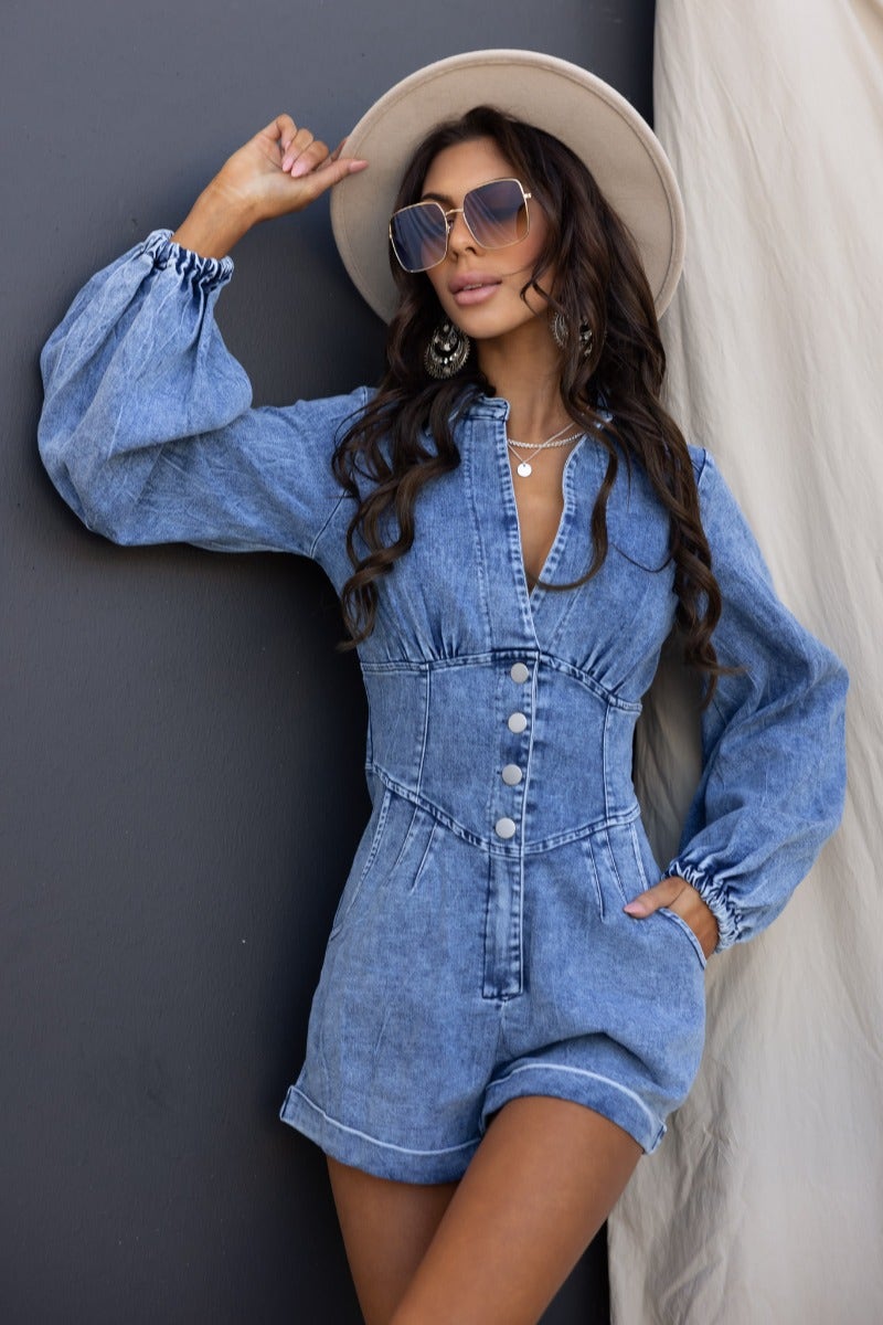 Stylish denim playsuit with V-neckline, button detail, and elastic cuffs, perfect for casual outings.