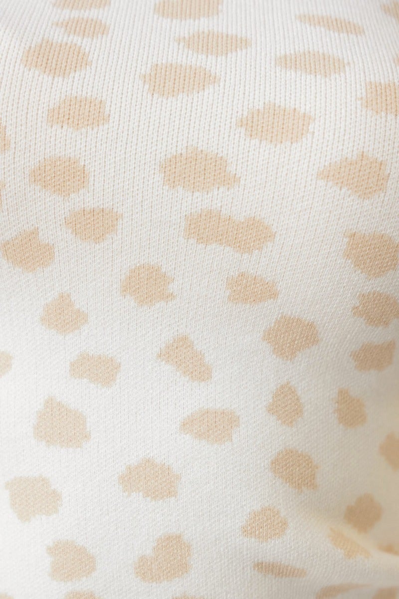 Close-up of a ribbed knit fabric featuring a beige leopard print pattern on a light background.