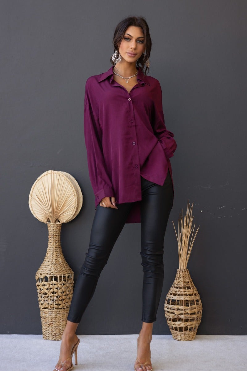 Model wearing a burgundy satin button-up Nori Top paired with leather pants, showcasing a relaxed fit.