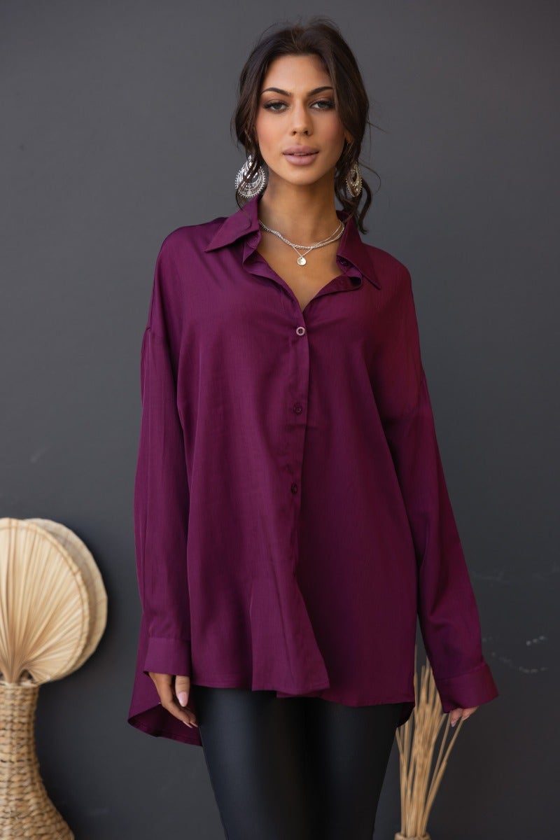 Model wearing a relaxed fit, purple satin button-up shirt with collar, paired with black pants, showcasing a chic style.
