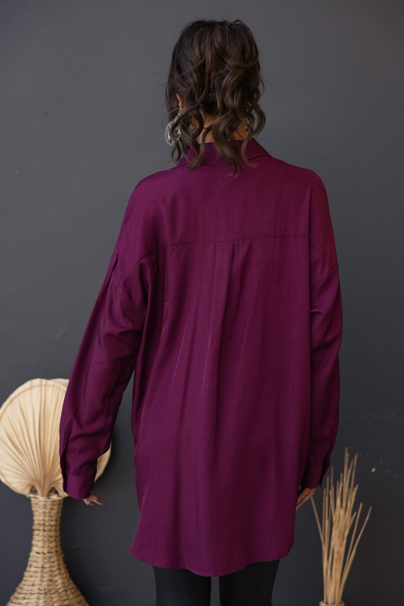Back view of a woman wearing a burgundy satin Nori Top shirt with relaxed fit, perfect for casual styling.