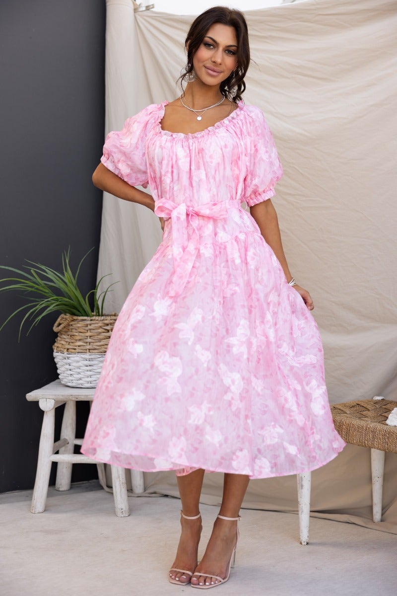 Pink embossed print midi dress with elastic neckline, removable belt, and puff sleeves, styled by a model.