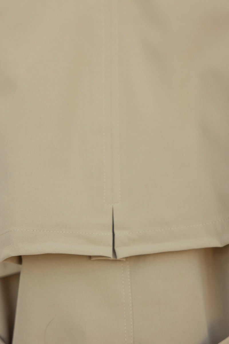 Detail of the Andie Jacket showing the hem and stitching in a soft beige color.