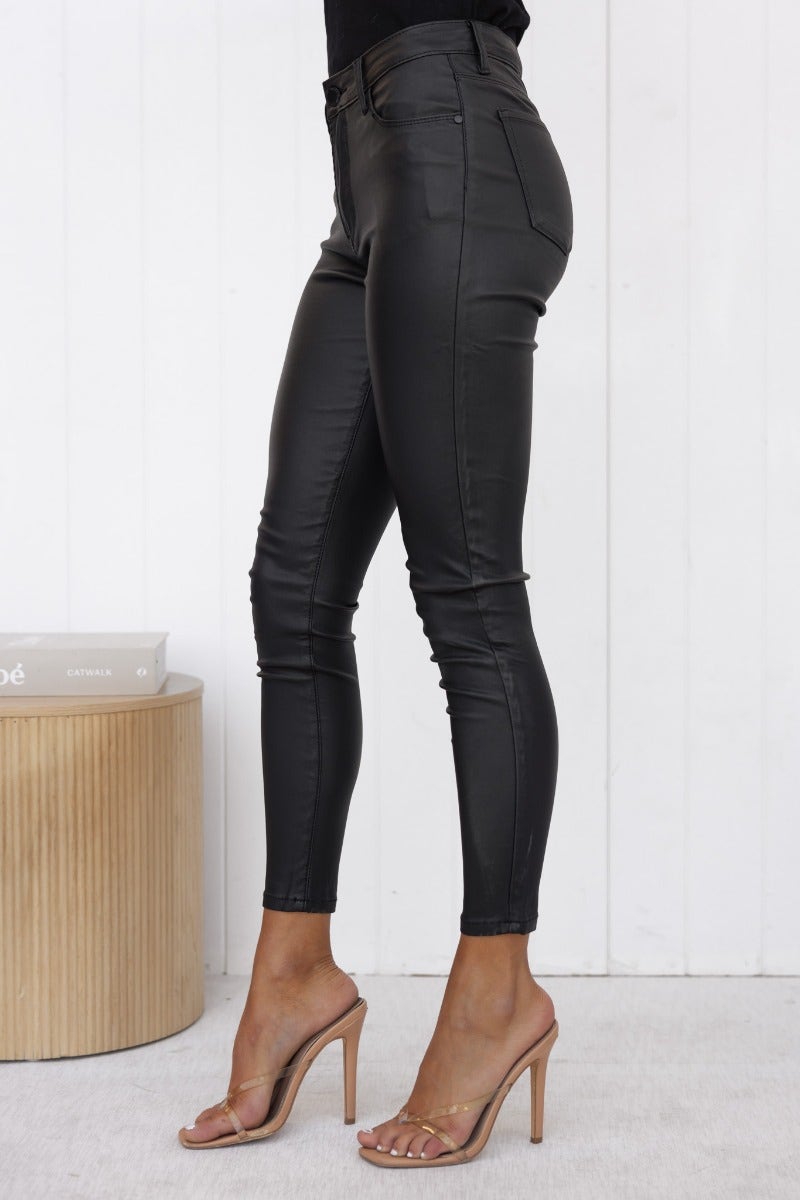 Side view of Harston wet look pants with mid-high waist, featuring a form-fitting design and pockets.
