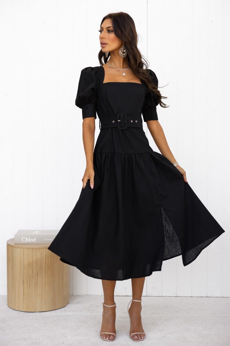 Woman wearing black linen blend Innis midi dress with square neckline, puff sleeves, and removable belt.