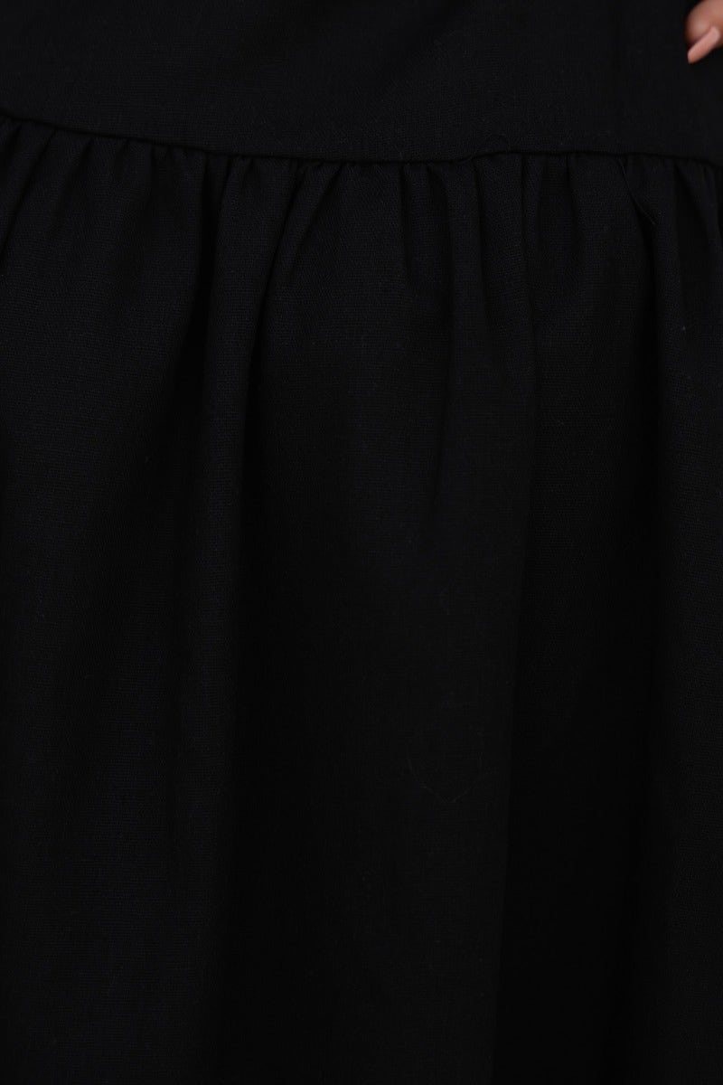 Close-up of black linen blend fabric detail of the Innis Midi Dress with gathered skirt and textured finish.