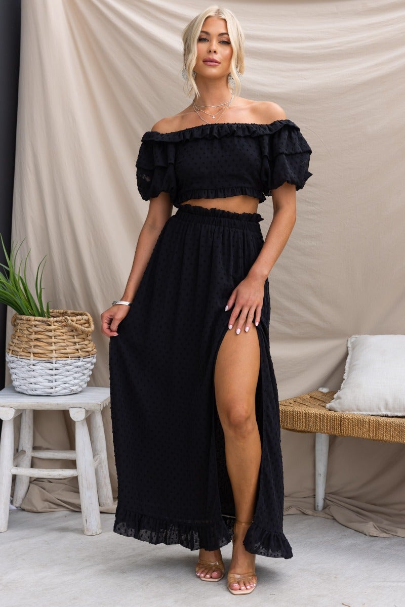 Model wearing a black textured off-shoulder Rosalia top with a matching skirt, showcasing its stylish design and elegant fit.