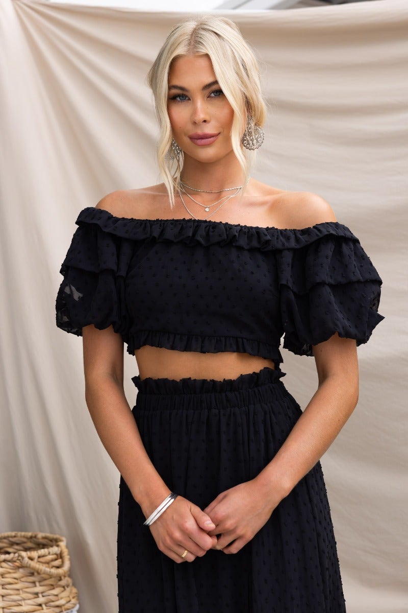 Off-shoulder black textured Rosalia top with ruffled sleeves, worn by model, featuring zip closure and lined design.