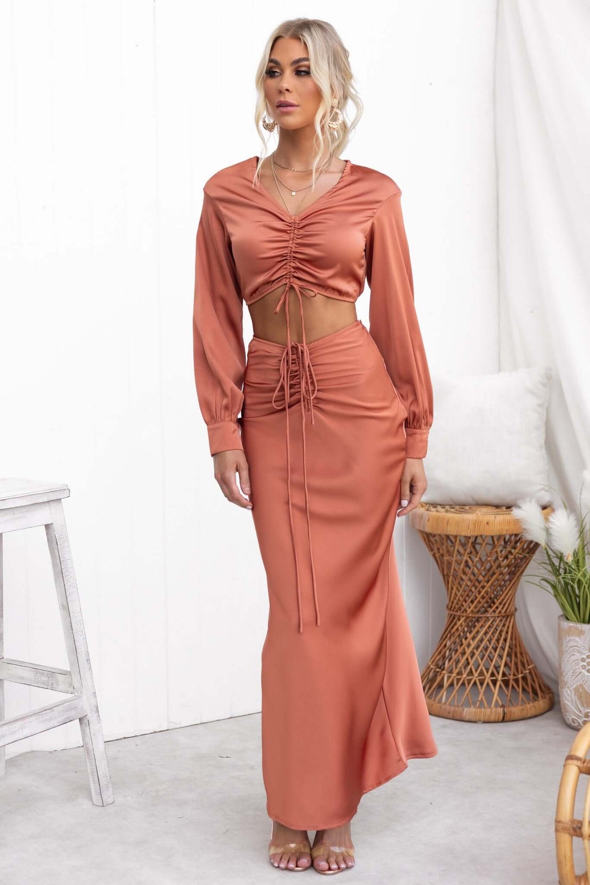 Model wearing Serene Top in rust color with V-neckline and adjustable ruching, paired with a matching skirt.