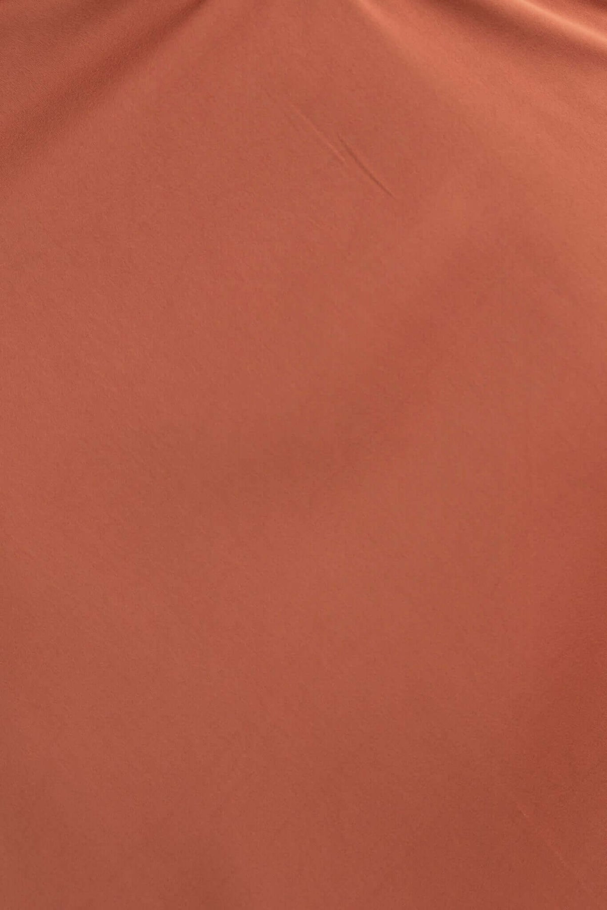 Close-up of soft, rust-colored fabric showcasing smooth texture for the Serene Top dress.