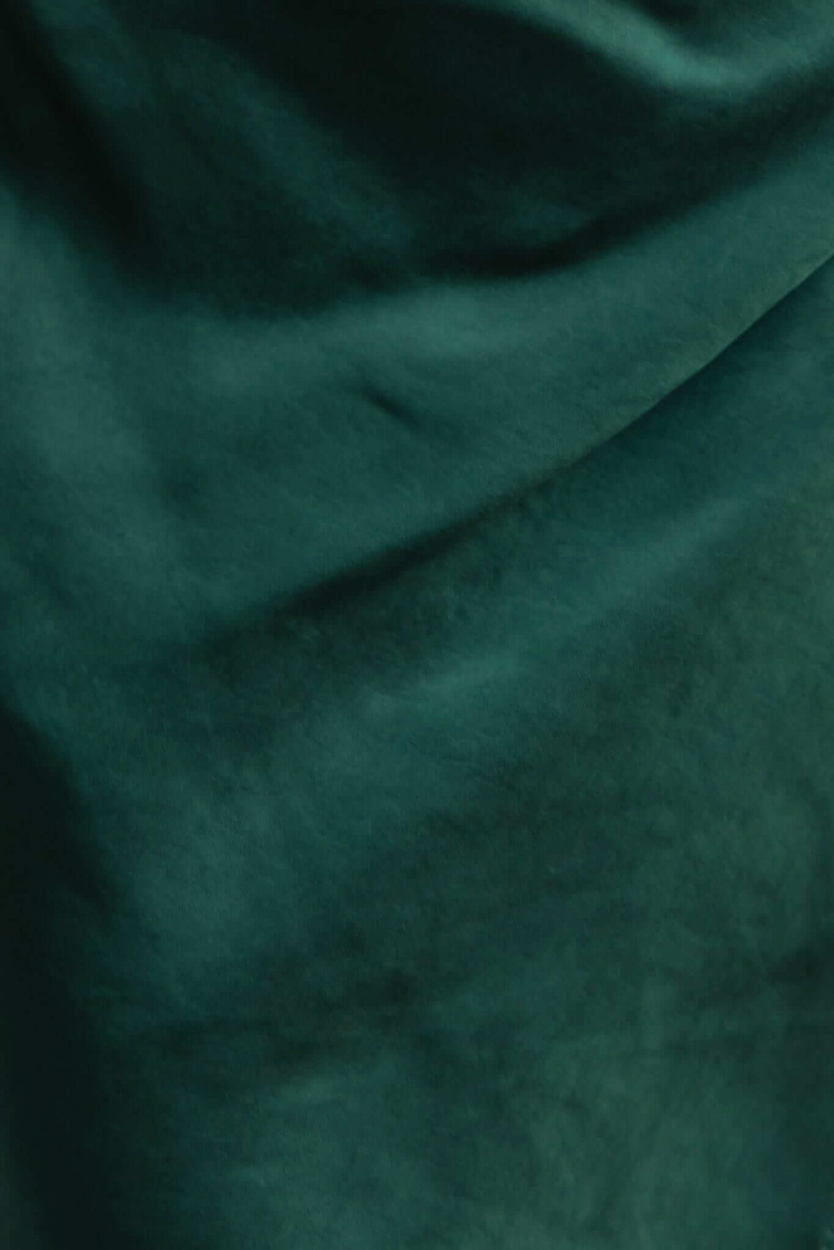 Close-up of luxurious green fabric showcasing a soft, satin-like texture and rich color.