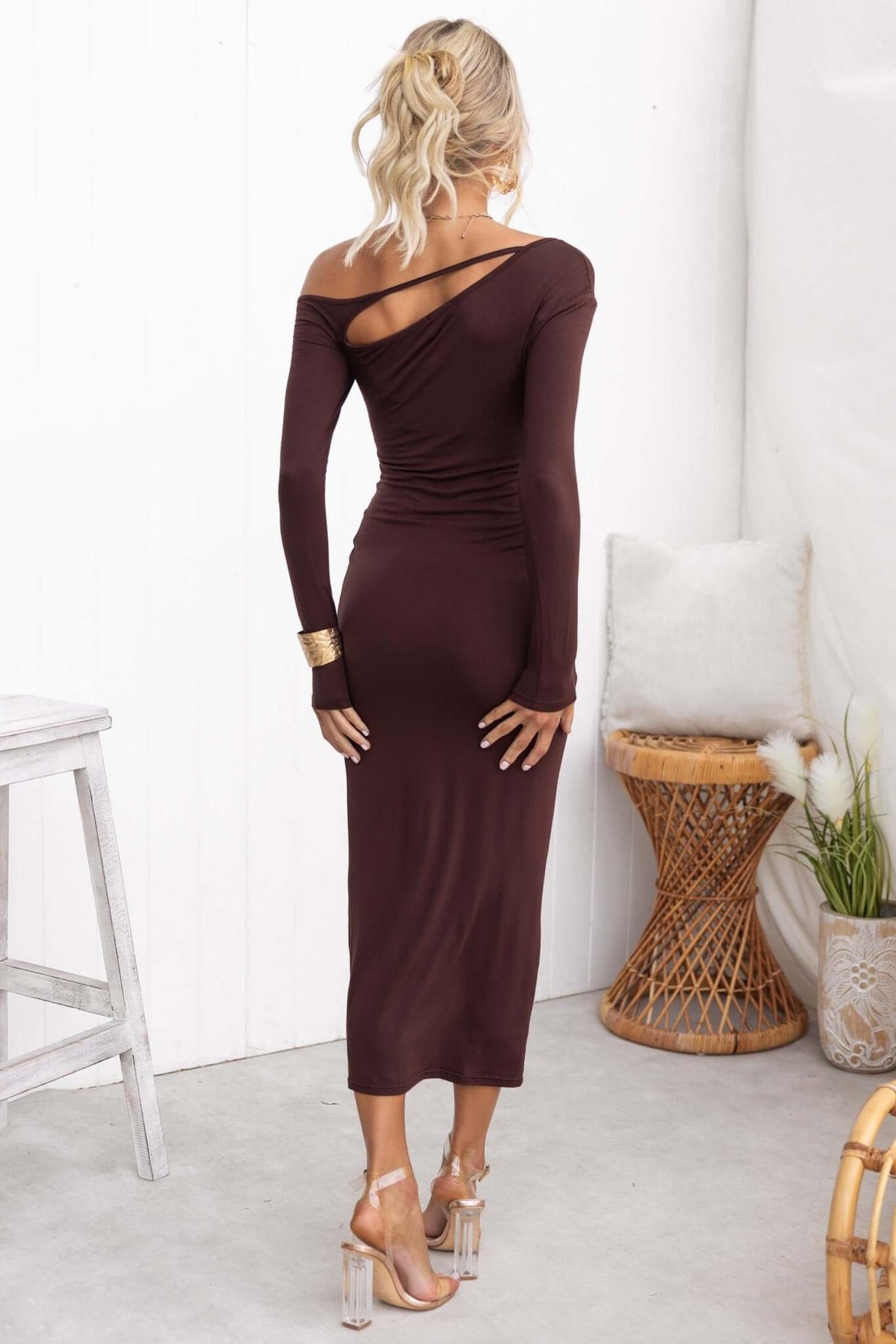 Back view of a woman in a cut-out maxi dress with long sleeves, featuring a sleek fit and elegant styling.