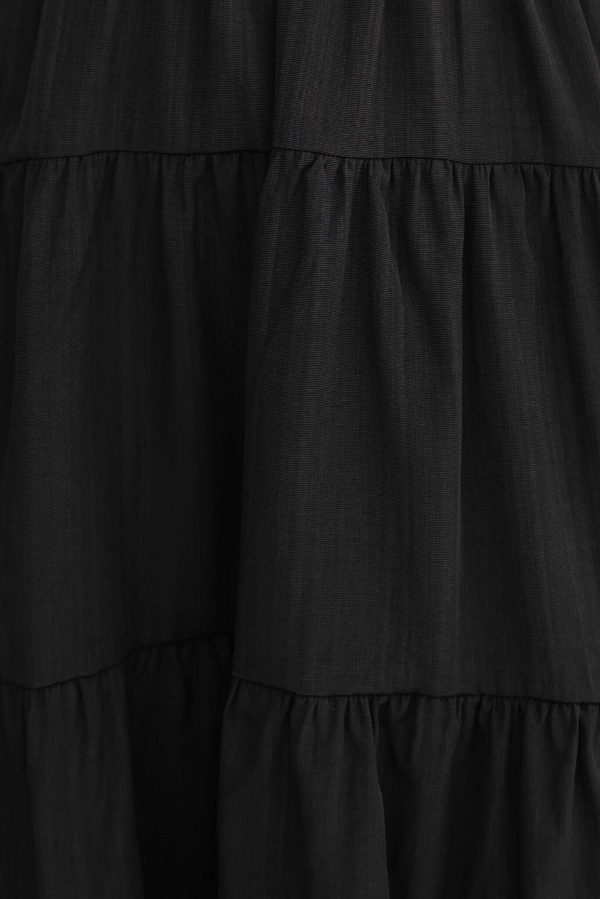 Close-up of the tiered black fabric of the Sakura Dress, showcasing its elegant texture and design detail.