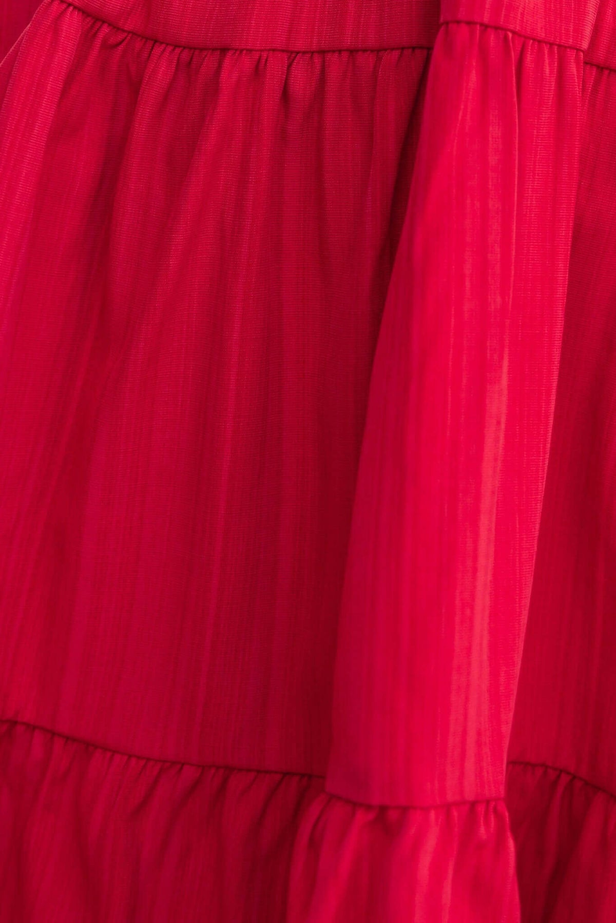 Close-up of the vibrant red Sakura Dress fabric featuring layered ruffles and a sleek texture.