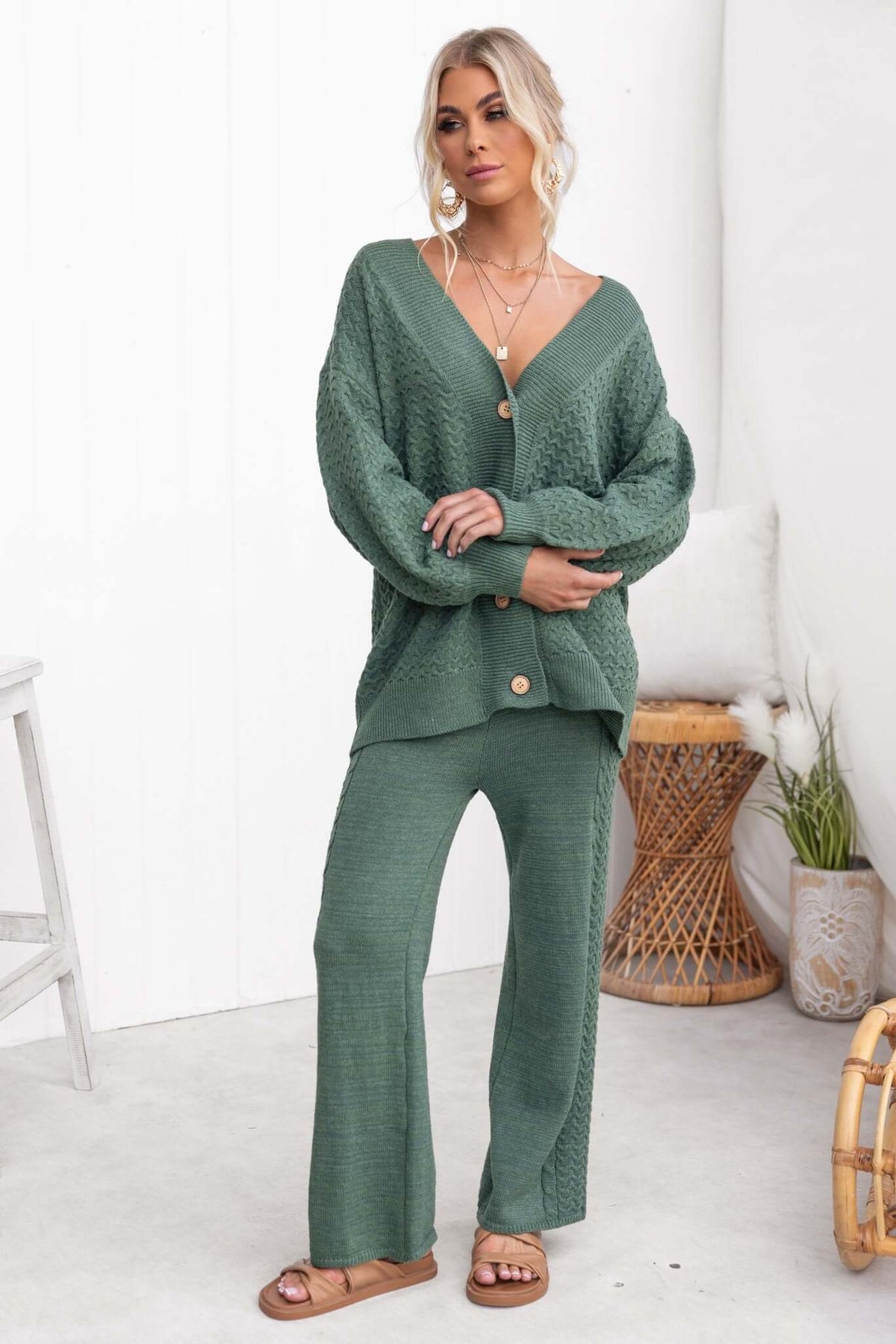 Woman in a green v-neck cardigan with button-up front and matching knit pants, showcasing a relaxed fit.