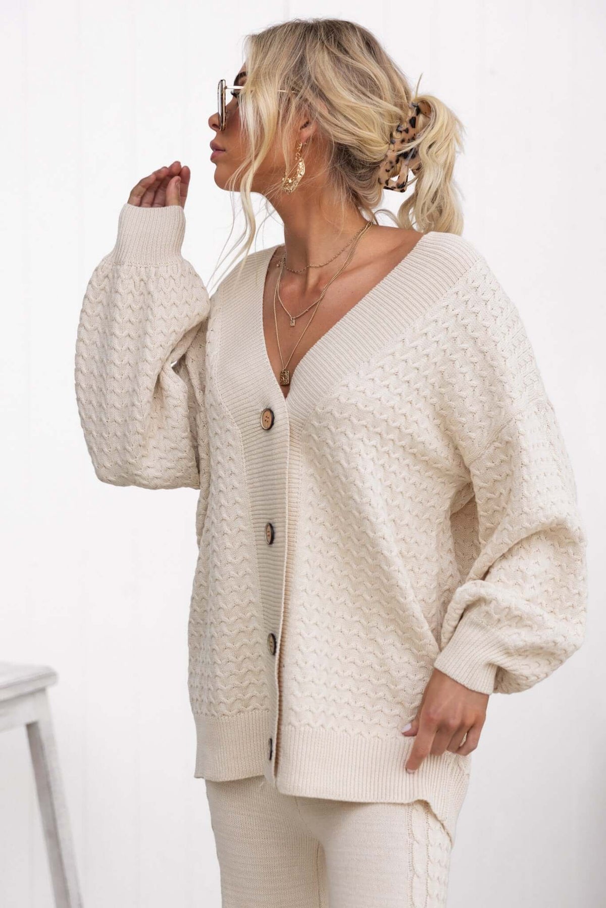 Cream V-neck cardigan with button-up front and oversized sleeves, perfect for relaxed style and comfort.