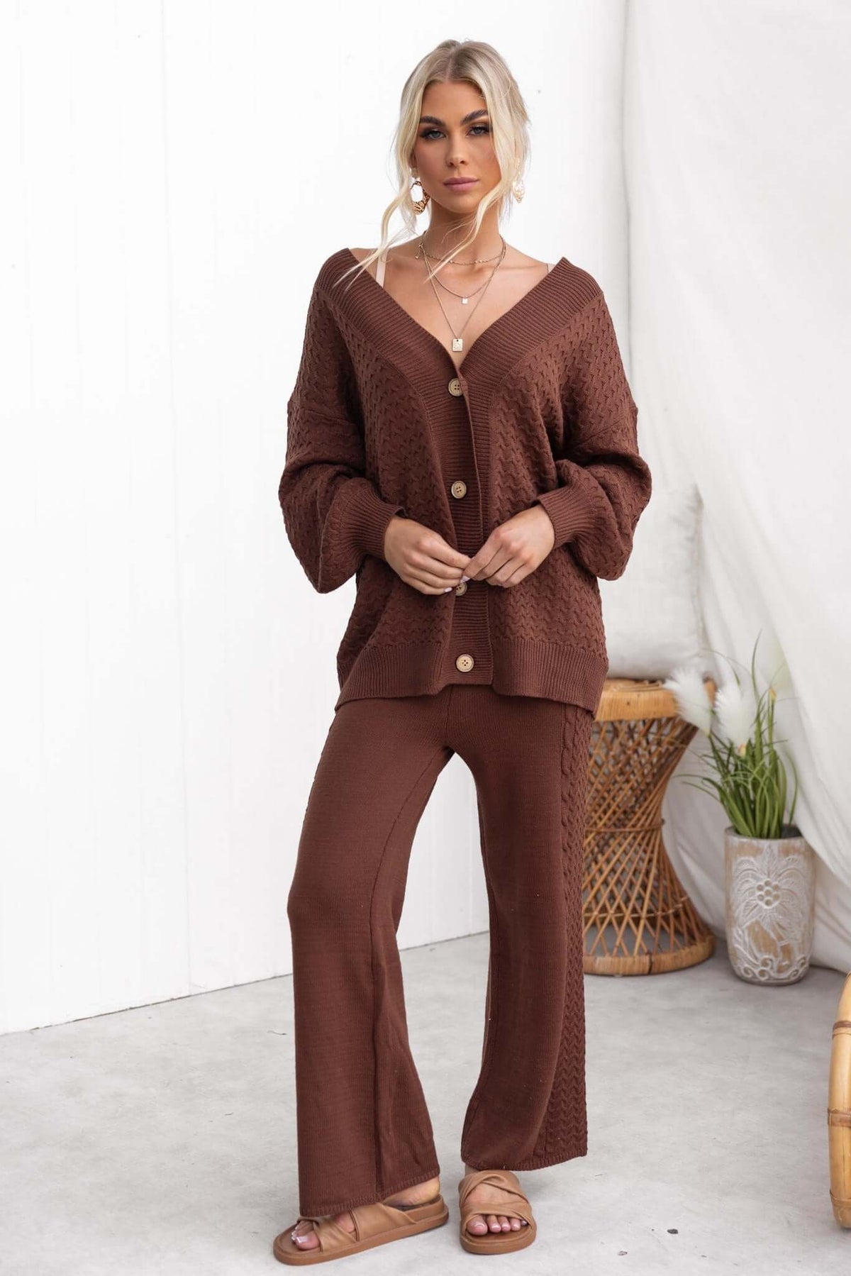 Woman in brown knit sweater and pants set, showcasing a relaxed style with a mid-high waist and button details.