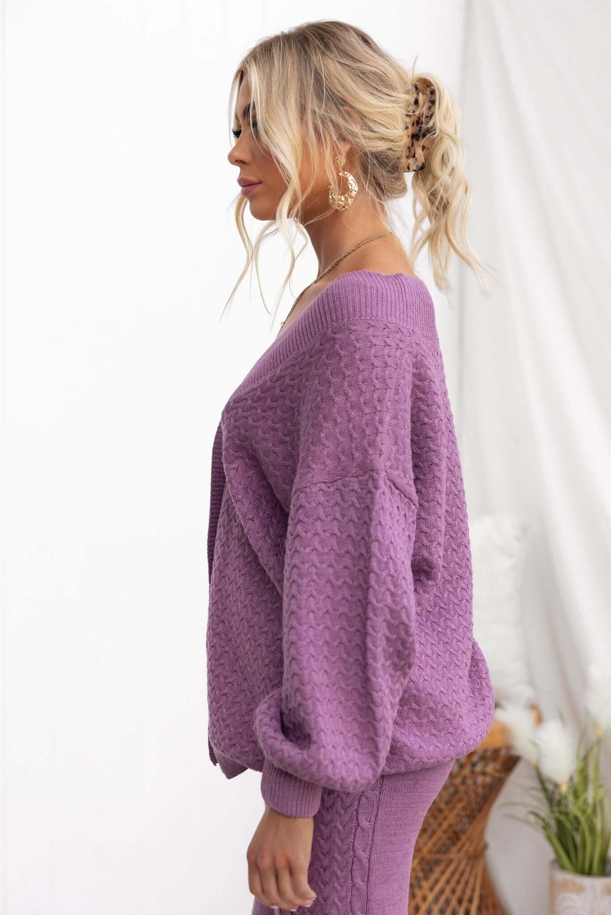 Side view of a woman wearing a relaxed-fit purple Jesse Cardigan with a V-neckline and balloon sleeves.