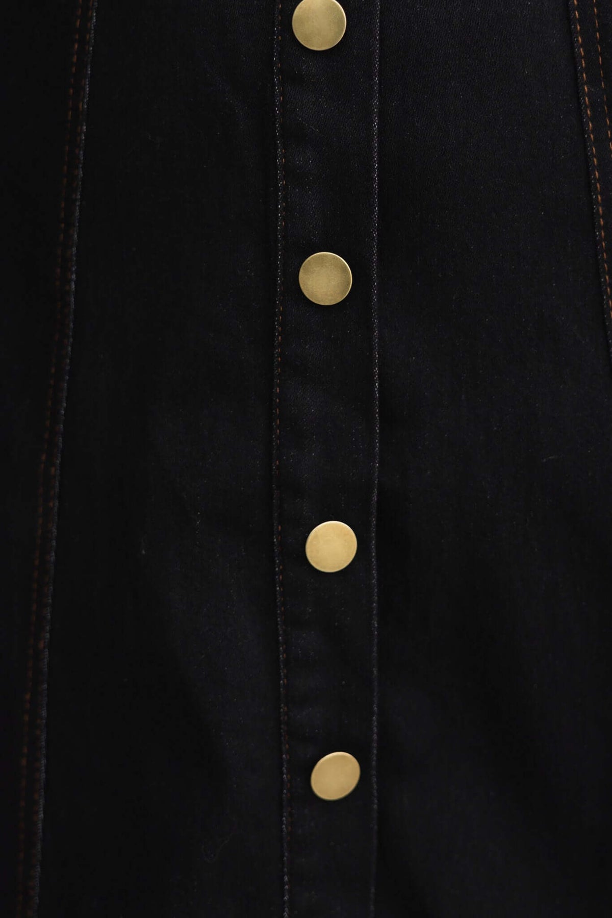 Close-up of black denim fabric with gold faux buttons on a maxi dress showcasing its stylish design.