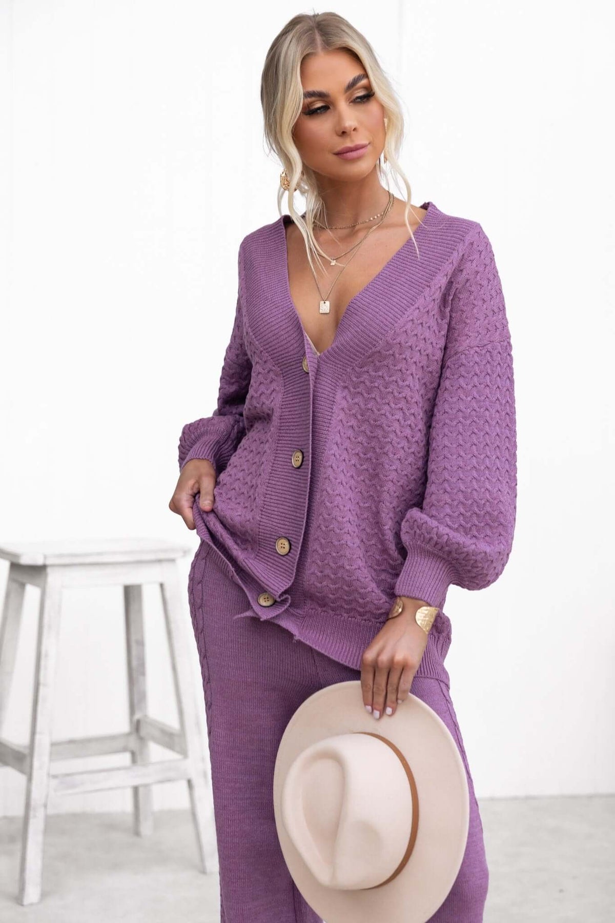 Jesse Cardigan in purple, featuring a V-neckline, button-up front, and relaxed fit, styled with a hat.