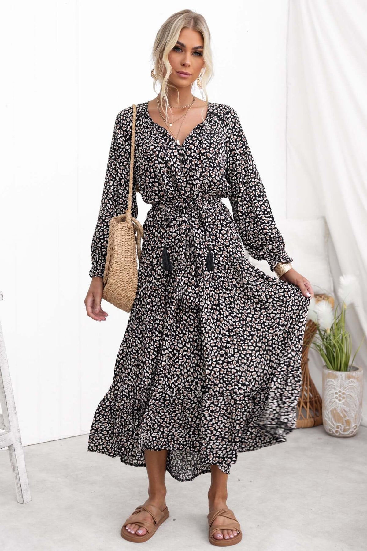 Model wearing a black midi dress with floral print, V-neckline, and removable belt, showcasing a relaxed fit.