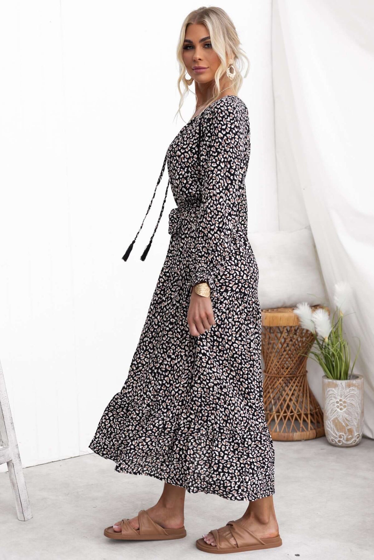 Black midi dress with floral print, V-neckline, and tie detail on sleeves, styled by a model.