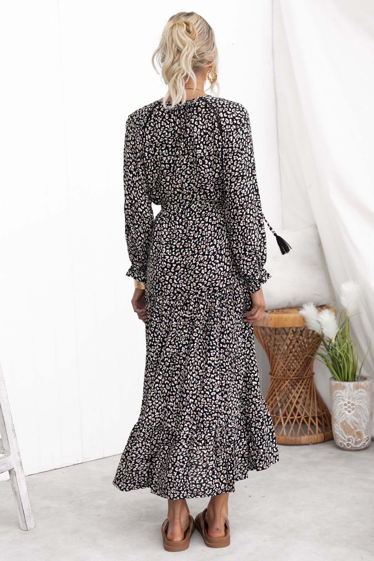 Back view of a black floral Maura Midi Dress with long sleeves, ruffled hem, and tie detail.