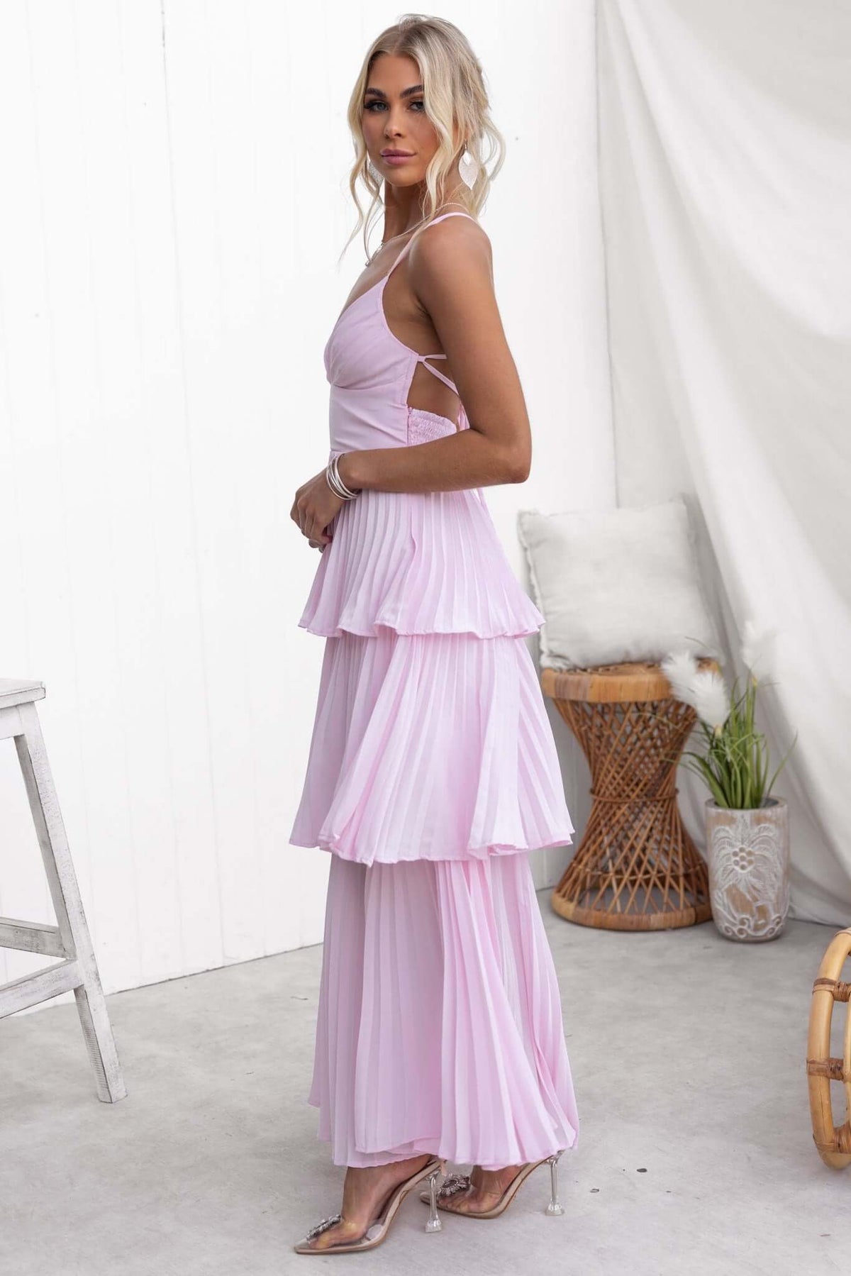 Model wearing the Remmy Maxi Dress featuring tie straps and pleated ruffle skirt in light pink.