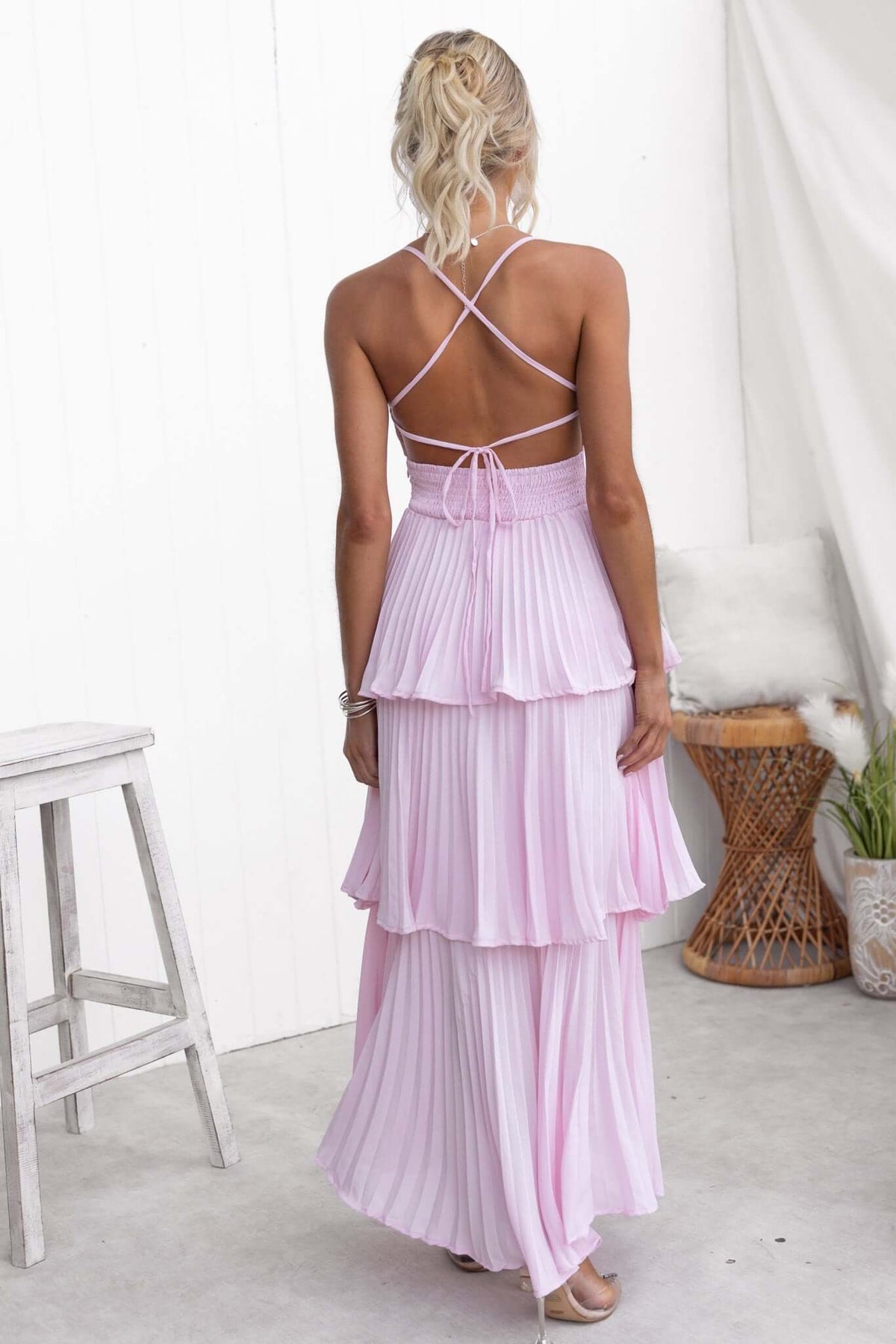 Back view of the Remmy Maxi Dress featuring tie straps, a pleated ruffle skirt, and an elegant pink color.