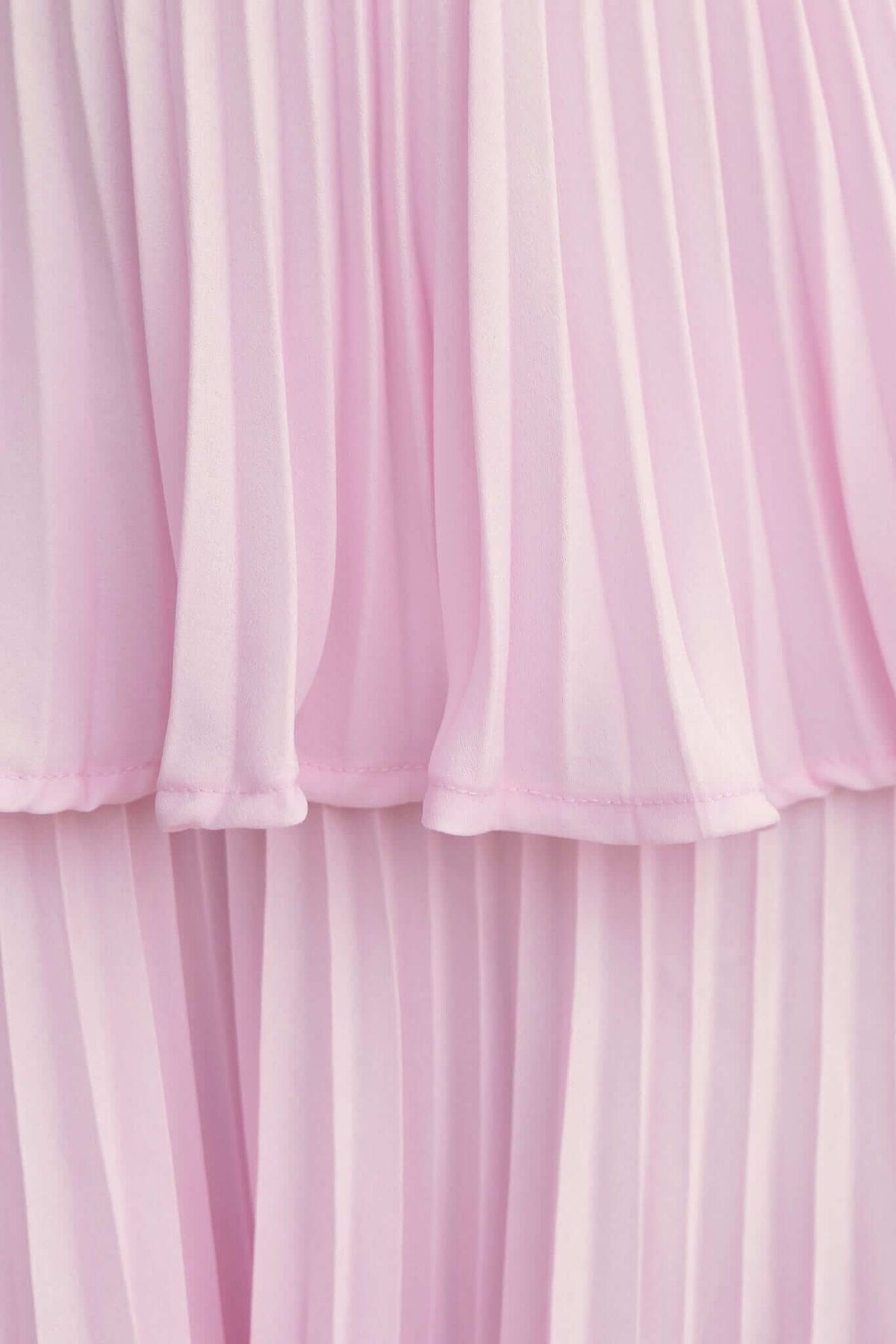 Close-up of the pleated ruffle skirt of the Remmy Maxi Dress in soft pink, showcasing its elegant layers and fabric texture.