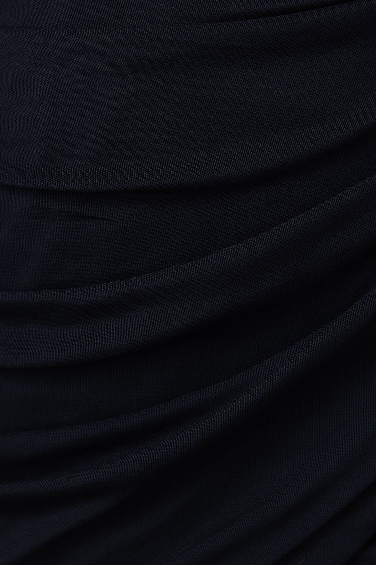 Close-up of the black fabric of the Never Stop Dress, featuring ruching detail and soft, stretchy texture.