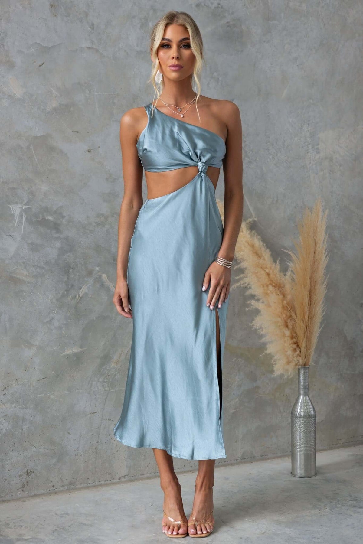 Model in blueprint midi dress featuring one-shoulder neckline, cut-out waist, and front split, styled with minimalist accessories.