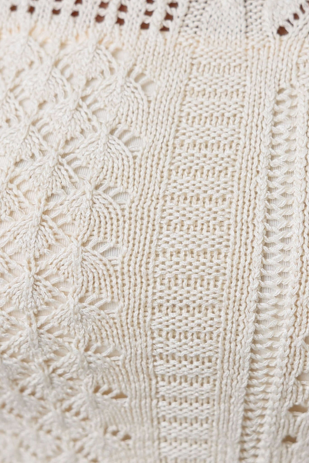 Close-up of intricate knit texture on the Perilla Top, showcasing cream-colored design and fine detailing.