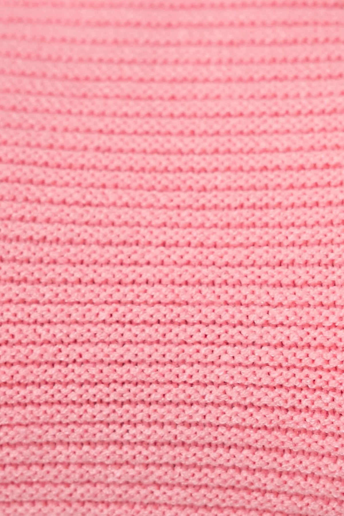 Close-up of textured pink knit fabric, showcasing soft stretch material for a cozy jumper.