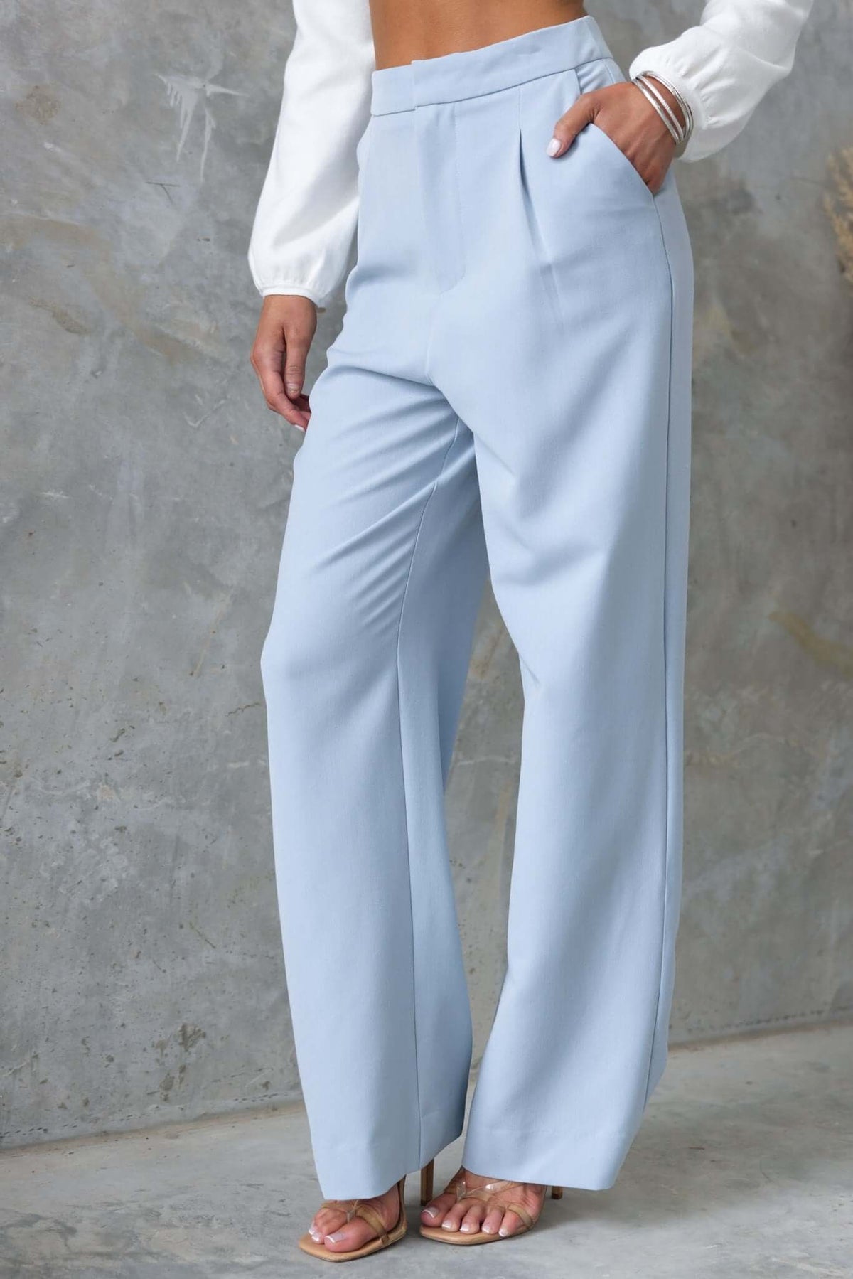 Kodi Pants in light blue with wide legs, mid-high waist, and pockets, styled with a chic top and heels.