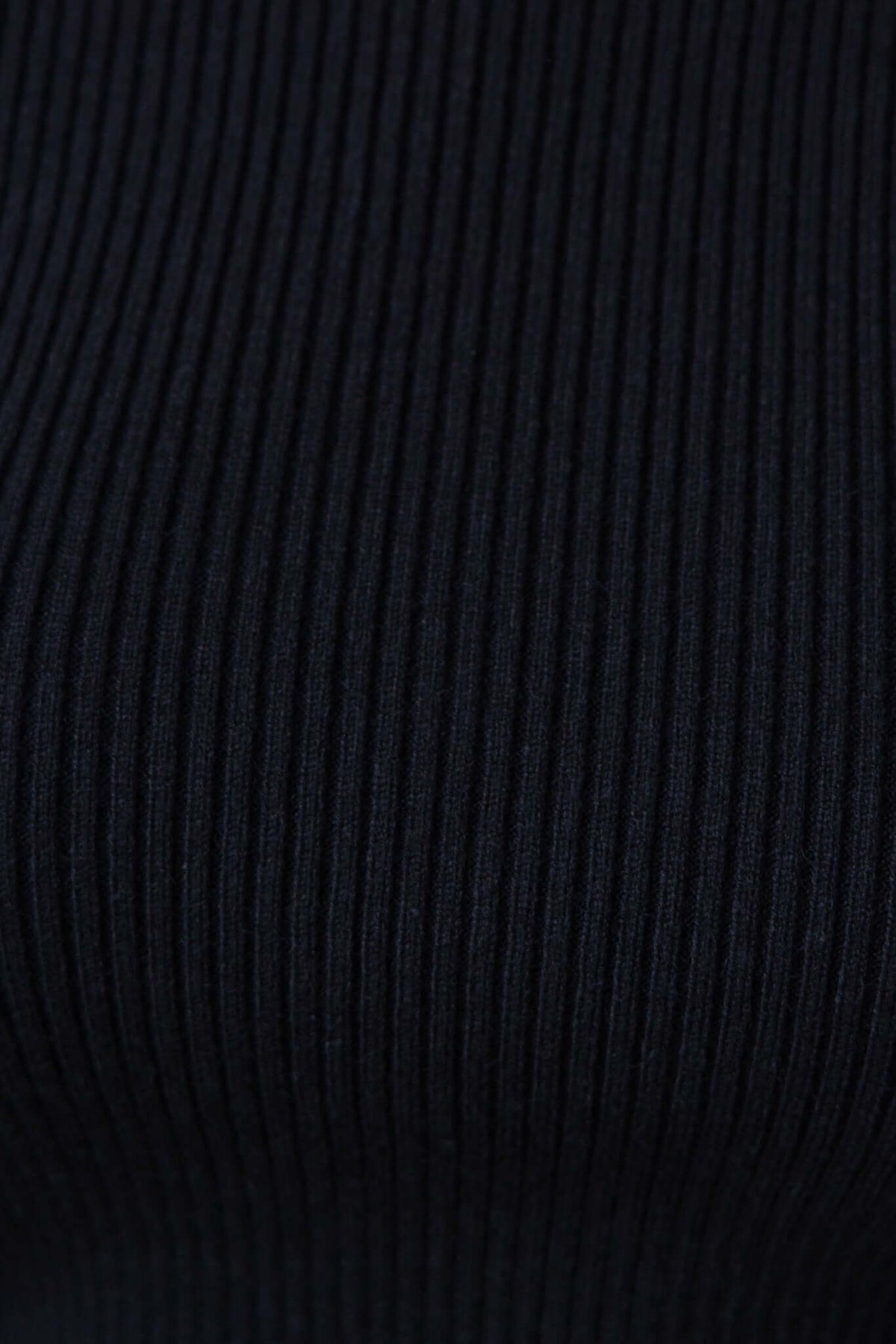Close-up of black ribbed knit fabric, showcasing texture and material stretch of Avola Top.