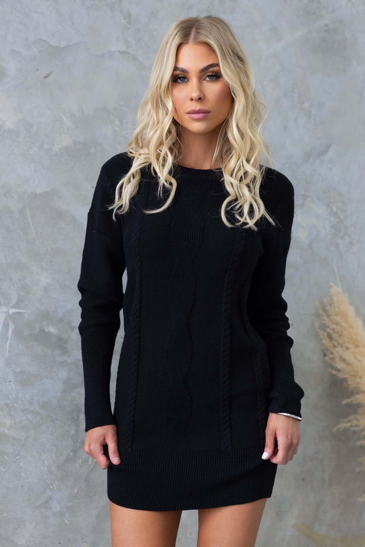 Model wearing the Beasley Dress, a black cable knit dress with a round neckline and relaxed fit.