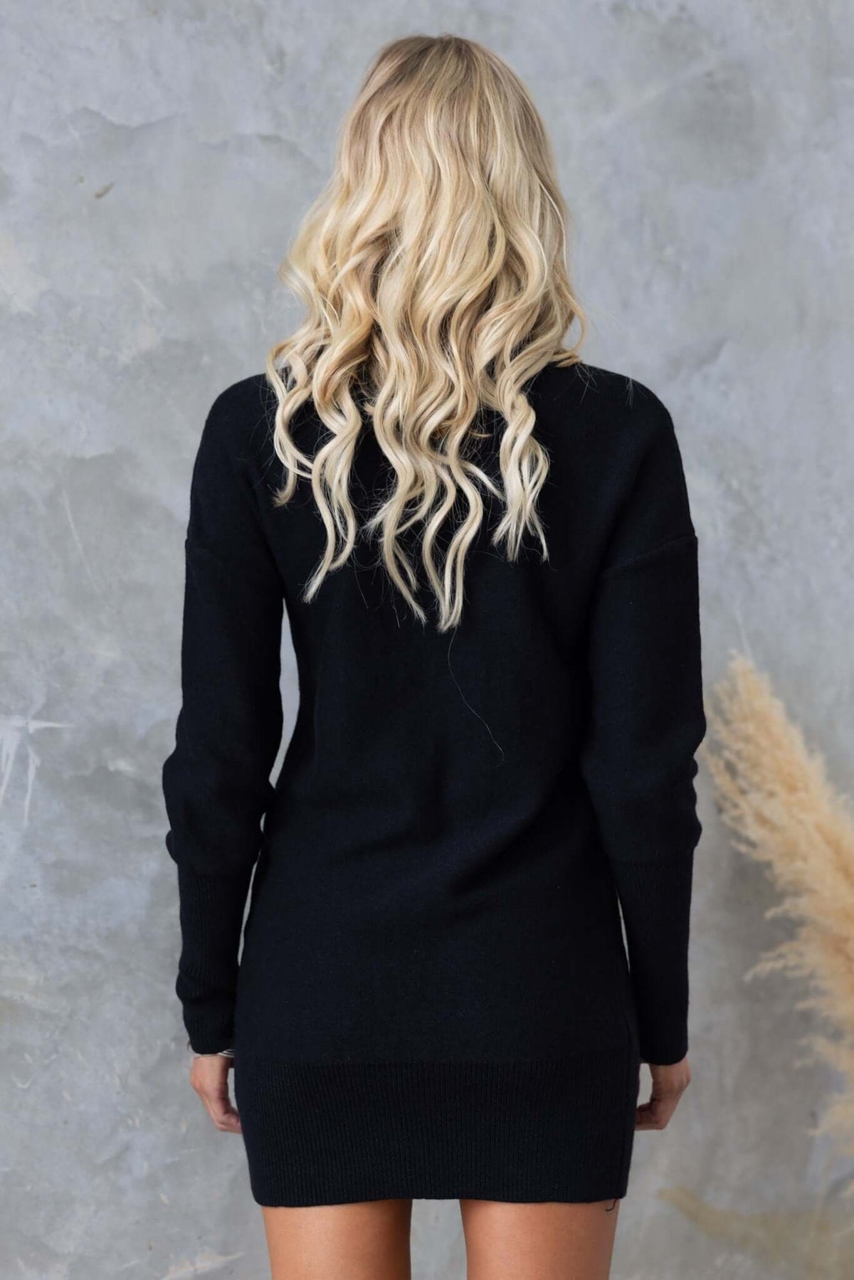 Model wearing the Beasley Dress, a black cable knit dress with a relaxed fit and long sleeves.