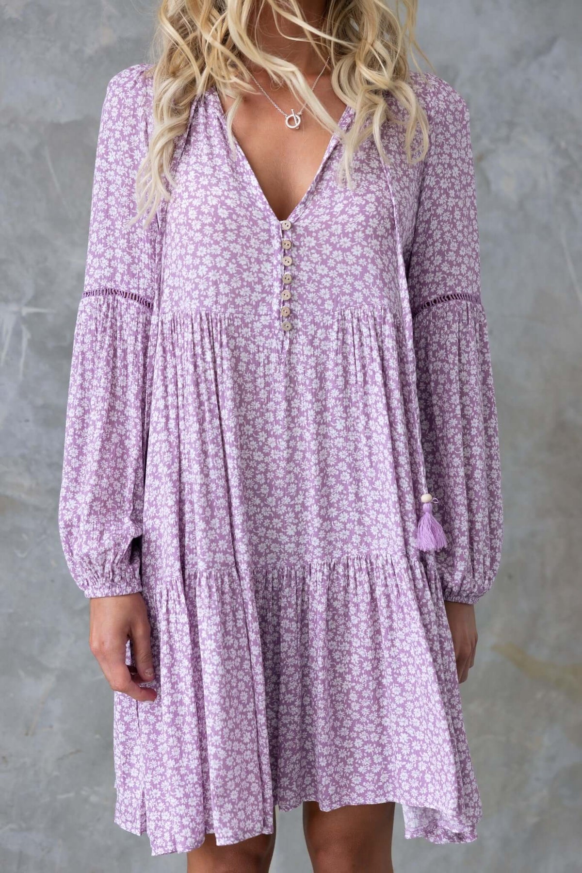 Lavender Fossa Dress with V-neckline, button-up detail, and tie accent on sleeves, styled for a relaxed fit.