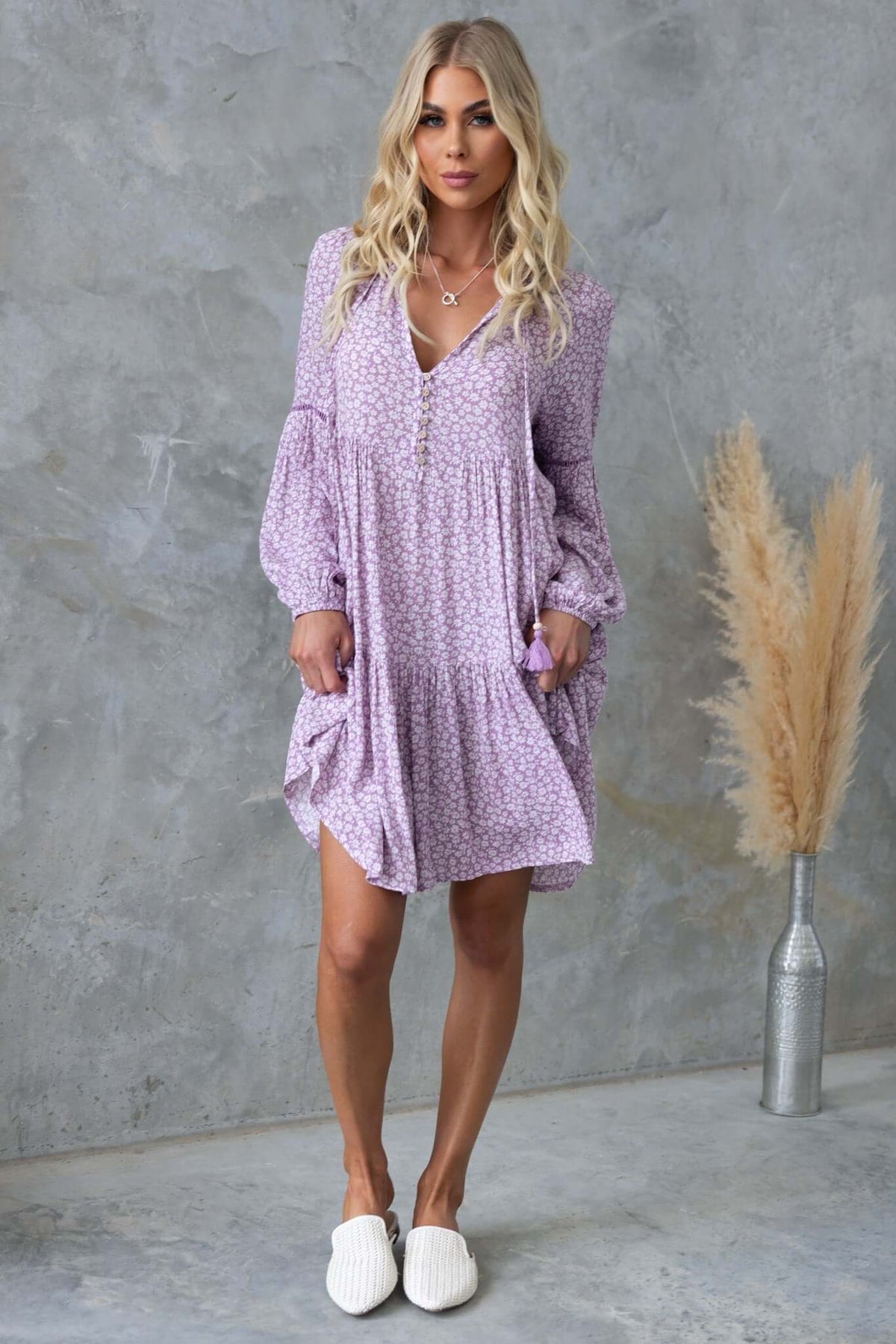 Model wearing a Fossa Dress with V-neckline and tie detail, featuring relaxed fit and floral pattern.